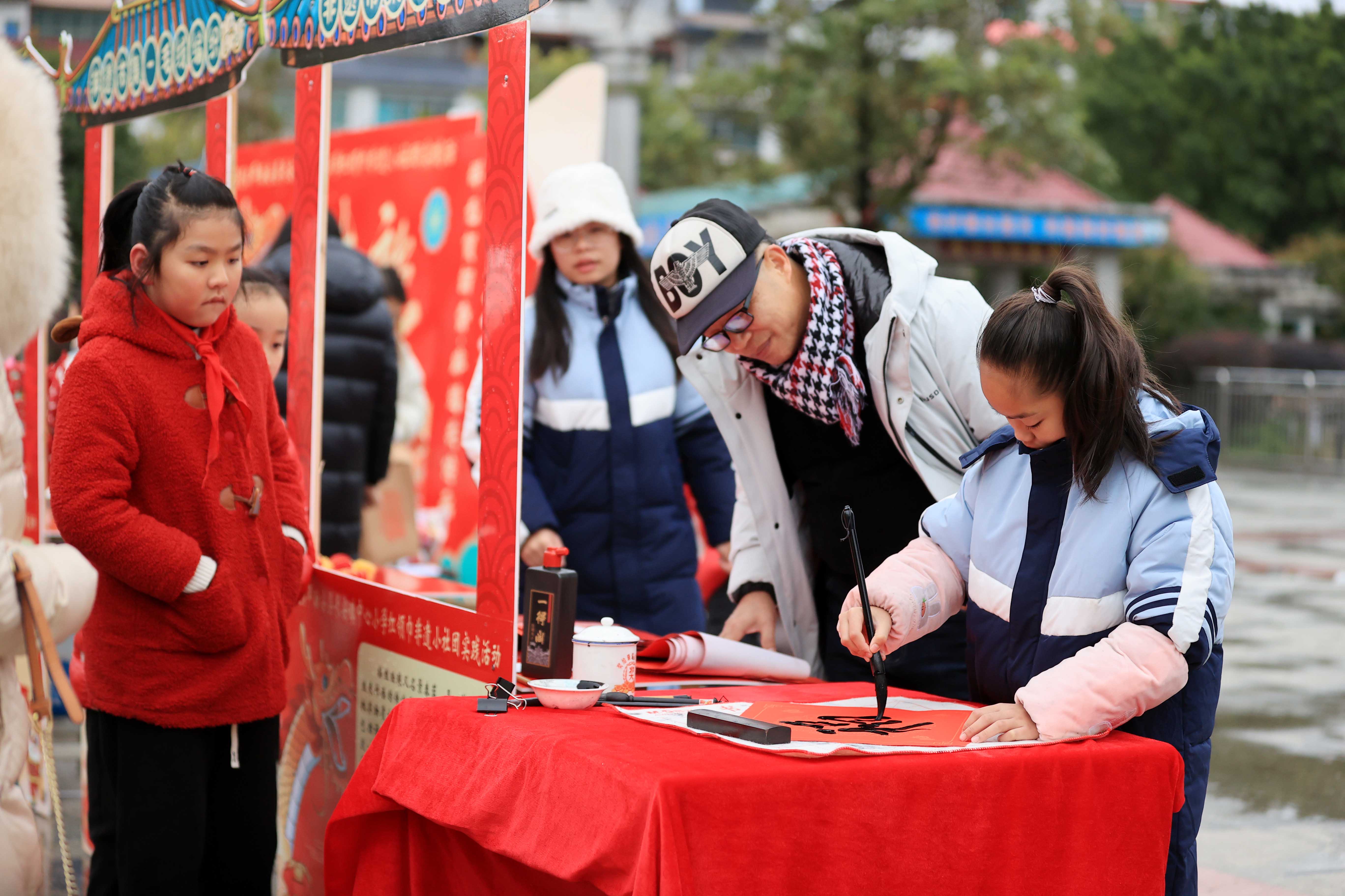 圖10：1月20日，在廣西柳州市融安縣長安廣場，一名小學(xué)生在書寫福字，準(zhǔn)備贈送市民。（譚凱興 攝）.JPG