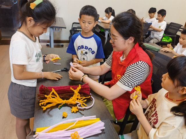 7月12日，在泰州市海陵區(qū)城東街道林湖社區(qū)，泰州市大浦小學(xué)“綠葉”暑期公益班的老師正在教孩子們一起做手工2（拍攝者：泰州市大浦中心小學(xué)  陳惠婷）.jpg